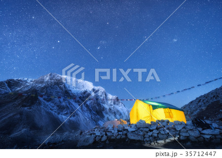 Yellow glowing tent against high rocks at night Yellow glowing tent against high rocks at night 35712447