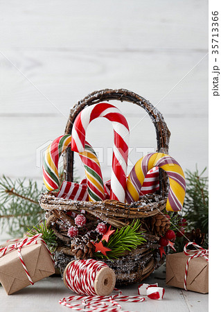 Christmas basket with candy canes on white planks 35713366