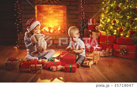 happy children open Christmas gifts at night at Christmas tree 35719047
