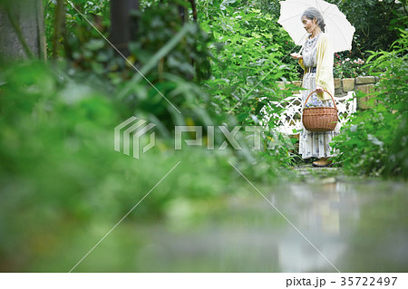 庭で日傘をさすシニア女性 庭で日傘をさすシニア女性 35722497