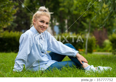 Happy relaxed student girl sitting on green grass 35777752