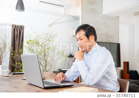 パソコンを見る中年男性　ミドル世代　中高年　短髪の男性　カジュアル　普段着　男の人 35780711