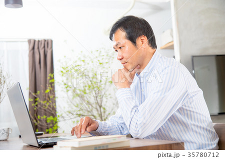 パソコンを見る中年男性　ミドル世代　中高年　短髪の男性　カジュアル　普段着　男の人 35780712
