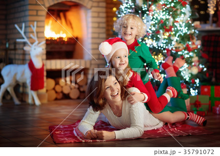 Family with kids at Christmas tree and fireplace. Family with kids at Christmas tree and fireplace. 35791072