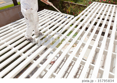 Professional Painter Rolling White Paint Onto The Top of A Home 35795834