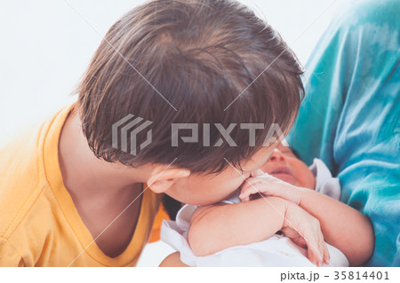asian child boy kissing his newborn baby sister asian child boy kissing his newborn baby sister 35814401