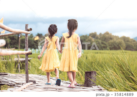 two little girls holding hand and walking together two little girls holding hand and walking together 35814889