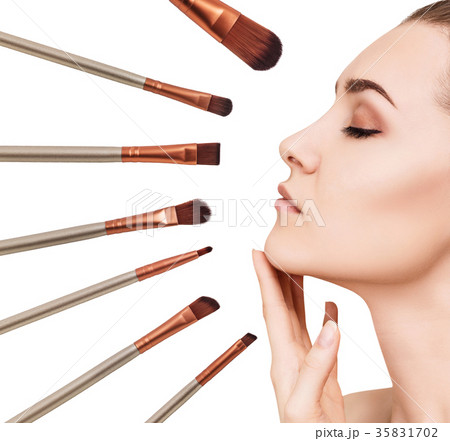 Woman's face surrounded by makeup brushes. 35831702