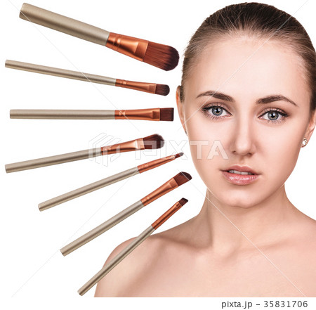 Woman's face surrounded by makeup brushes. 35831706
