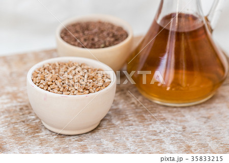 Wheat grains in wooden bowl and oil in decanter 35833215