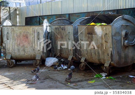 Dumpsters being full with garbage in a city. 35834038