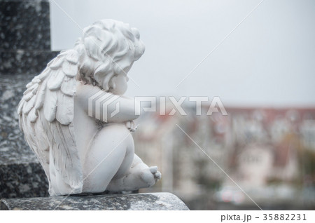 stoned angel sitting on tomb in a cemetery 35882231