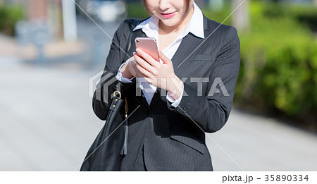 スマホを持ったスーツの女性の手元 Ol ビジネス スーツ ポートレート リクルート 緑背景 の写真素材