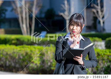 手帖を持ったスーツの女性　OL　ビジネス　スーツ　ポートレート　リクルート　緑背景　 35891187