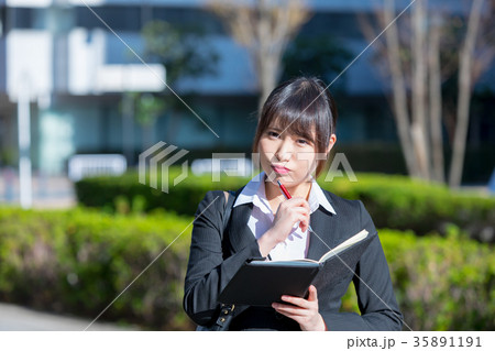 手帖を持ったスーツの女性　OL　ビジネス　スーツ　ポートレート　リクルート　緑背景　 35891191