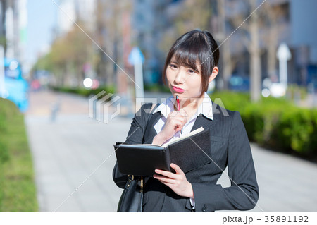 手帖を持ったスーツの女性　OL　ビジネス　スーツ　ポートレート　リクルート　緑背景　 35891192
