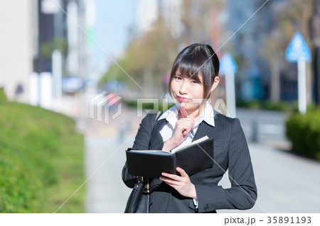 手帖を持ったスーツの女性　OL　ビジネス　スーツ　ポートレート　リクルート　緑背景　 35891193