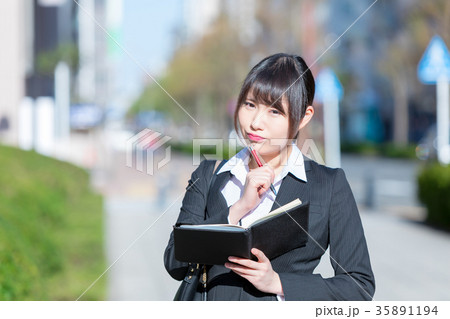 手帖を持ったスーツの女性　OL　ビジネス　スーツ　ポートレート　リクルート　緑背景　 35891194