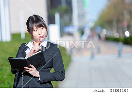 手帖を持ったスーツの女性　OL　ビジネス　スーツ　ポートレート　リクルート　緑背景　 35891195