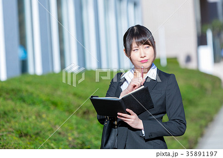 手帖を持ったスーツの女性　OL　ビジネス　スーツ　ポートレート　リクルート　緑背景　 35891197