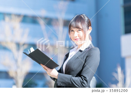 手帖を持ったスーツの女性　OL　ビジネス　スーツ　ポートレート　リクルート　緑背景　 35891200