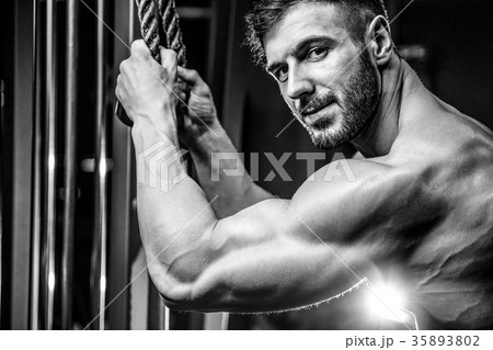 Handsome model young man training arms in gym Handsome model young man training arms in gym 35893802