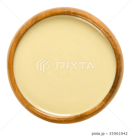 White almond butter in wooden bowl over white White almond butter in wooden bowl over white 35901942