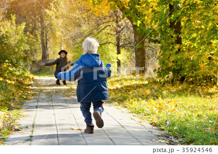 Blond boy runs to meet her mother. Autumn park Blond boy runs to meet her mother. Autumn park 35924546