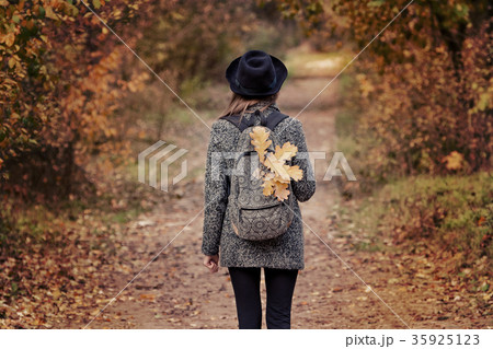 Girl in a hat with backpack is standing in forest. 35925123