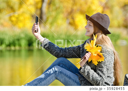 Girl in hat sitting on the dock and makes selfie 35928455