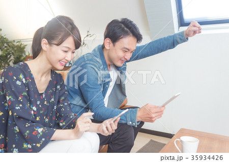 スマホを見て喜ぶカップル スマホを見て喜ぶカップル 35934426