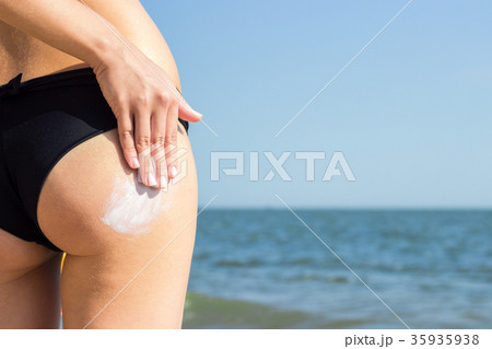 girl applying suntan lotion on her buttocks 35935938