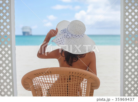 Young pretty girl sitting on the beach back view 35969437