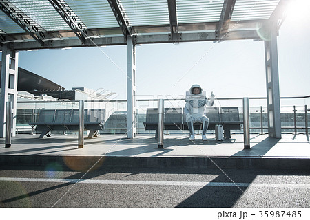 Concerned cosmonaut in white armor sitting outside 35987485