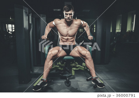 Handsome model young man training legs in gym 36000791