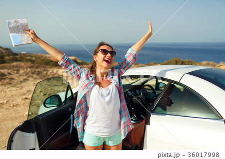 Joyful woman with a map traveling on a cabriolet Joyful woman with a map traveling on a cabriolet 36017998