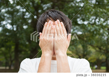 顔を隠す男性の写真素材