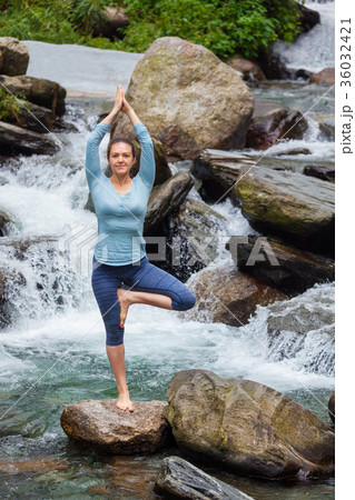 Woman in yoga asana Vrikshasana tree pose at Woman in yoga asana Vrikshasana tree pose at 36032421