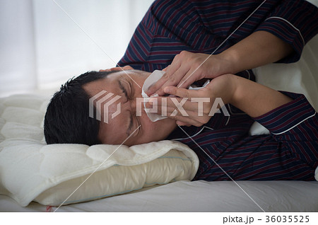ベッドで鼻をかむ若い男性 36035525