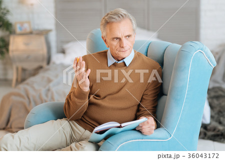 Pensive senior gentleman gesturing while writing 36043172