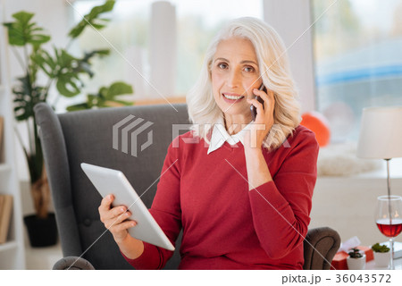 Pretty senior lady talking on smartphone at home Pretty senior lady talking on smartphone at home 36043572