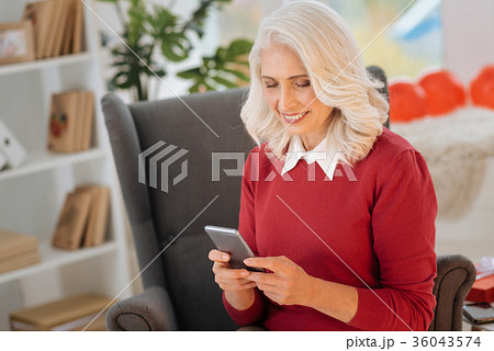 Positive minded lady using her smartphone at home Positive minded lady using her smartphone at home 36043574