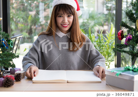 asian woman wear santa claus hat at home. girl with notebook, gift present box, christmas tree. xmas, new year celebration. season greetings asian woman wear santa claus hat at home. girl with notebook, gift present box, christmas tree. xmas, new year celebration. season greetings 36049871