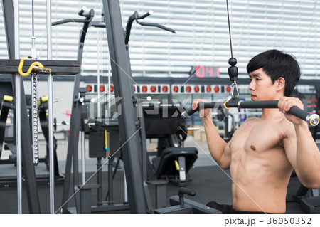 young man execute exercise with weightlifting machine in fitness center. male athlete pump up muscle with pull down machine in gym. sporty guy working out in health club. 36050352