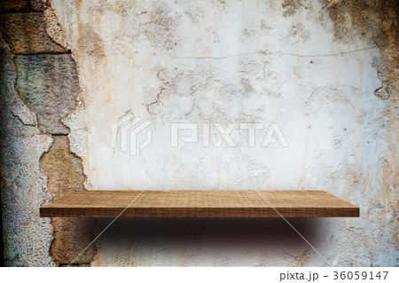 Empty wooden shelves display on cracked brick wall 36059147