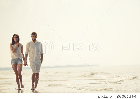 Happy fun beach vacations couple walking together Happy fun beach vacations couple walking together 36065364