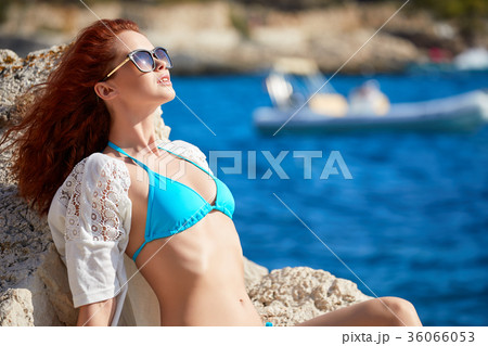 Redhaired woman in bikini relaxed on quiet sea with warm sun col Redhaired woman in bikini relaxed on quiet sea with warm sun col 36066053