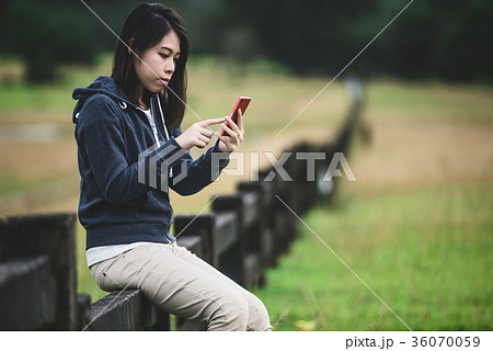 Happy young woman sitting on fence. 36070059
