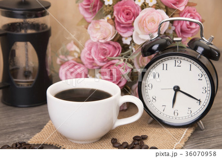 Hot cup of coffee and alarm clock on wood table  36070958