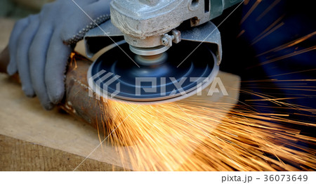 Worker cutting metal with grinder 36073649